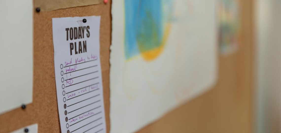 Close-up of a corkboard with a to-do list and colorful artwork in an office setting.