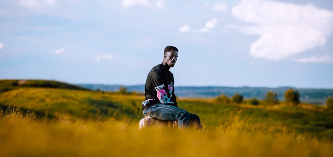 man in black jacket sitting on green grass field during daytime